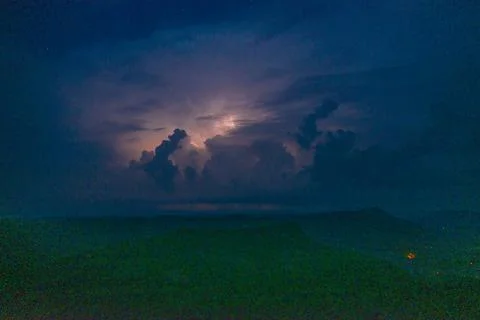 Lightning illuminates storm clouds at night Stock Photos