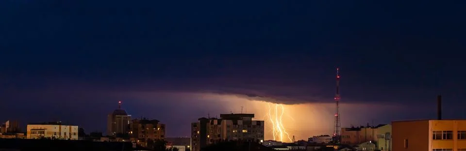 Lightning over city. Panoramic dramatic view. Thunderstorm and dark storm clouds Stock Photos