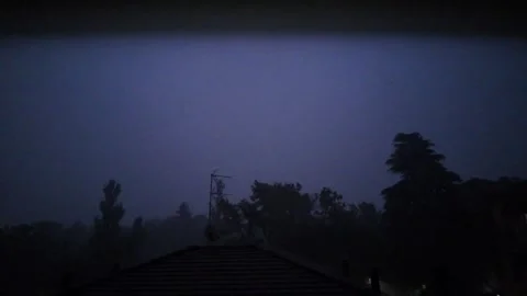 Lightning storm at night with house rooftop and trees swaying in the wind Stock Footage 339068353