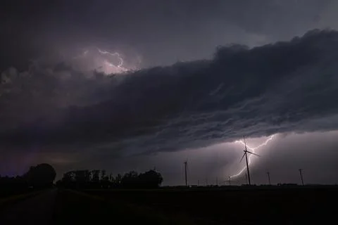 Lightning storm over wind farm at night, dramatic clouds and flashing bolts Foto stock