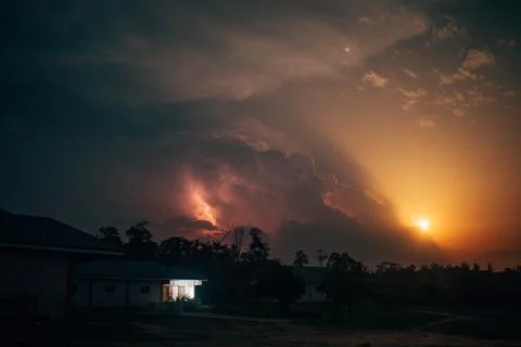 A lightning storms in the clouds as a summer moon rises Stock Photos