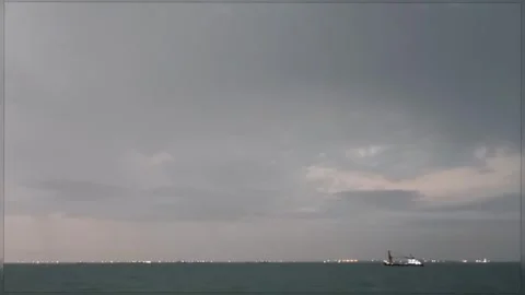 Lightning Strike Over the Sea with Ship and Distant City Lights at Night 4K Stock Footage 346683227
