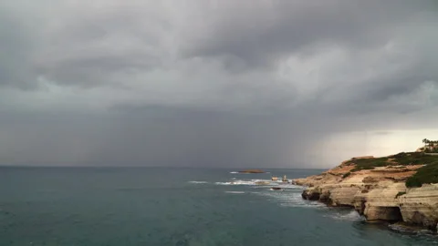 Lightning strike over stormy sea with dark clouds above coastal cliffs landscape Stock Footage 323355752
