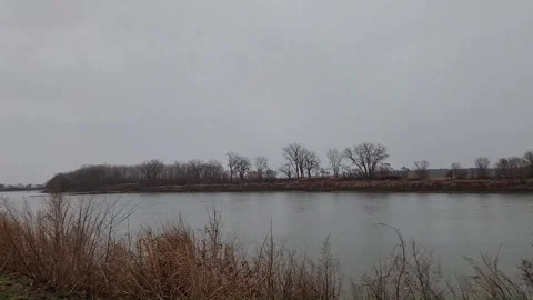 Lightning strike over wide river during daytime thunderstorm in winter landscape Stock Footage 330923191