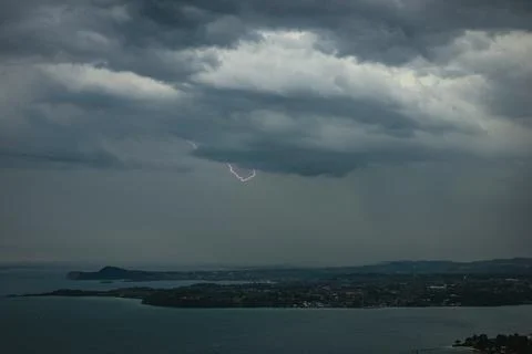 Lightning strike under dark storm clouds over Lake Garda, Italy at dawn Fotos Stock
