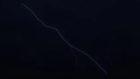 Lightning strikes across the dark sky during a storm at Stock Footage 338329907