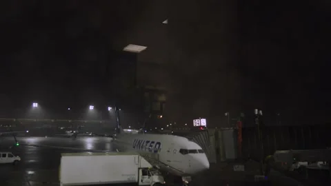 Lightning strikes behind a passenger jet waiting on the tarmac gate of the a Stock Footage 241498161