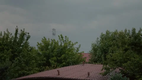 Lightning strikes in blue sky near high voltage wires and trees during storm Stock Footage 318821128