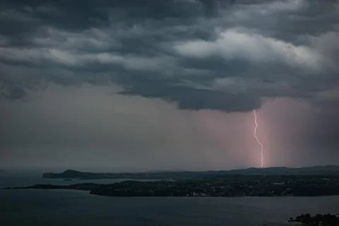 Lightning strikes from a dramatic stormy sky at the shore of Lake Garda, Italy Stock Photos