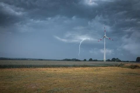 A lightning strikes the ground next to a wind turbine Stock Photos