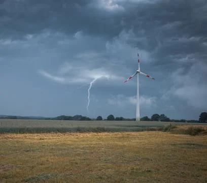 A lightning strikes the ground next to a wind turbine Stock Photos