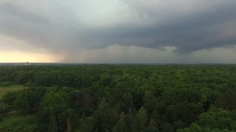 Lightning strikes viewed in the distance by drone rising over forest Stock Footage 94864667