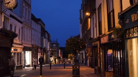 Lights come on as evening comes to Abbeygate Street in Bury St Edmunds Stock Footage 96773031