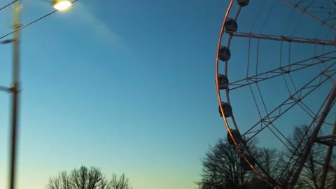Lights flicker as ferris wheel turns slowly, Twilight backdrop showcases Vídeos de archivo 324767294