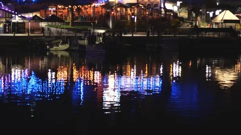 Lights from river walk shops reflecting on the water at night Stock Footage 123912471