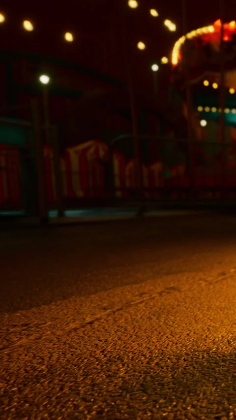 Lights shine on the ground of an empty amusement park at night Stock Footage 339774434