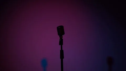 Lights of spotlights are getting brighter and shine on a chrome mic in darkness. Stock Footage 118527410