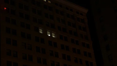 Lights turning on in old apartment complex in downtown city at night Stock Footage 85108145