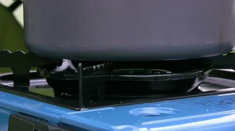 Lightweight camping pan is placed on a single ring butane gas camping stove Stock Footage 50527347