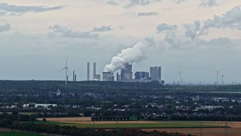 Lignite-fired power plant emitting smoke and steam with wind turbines in Germany Stock Footage 344426948
