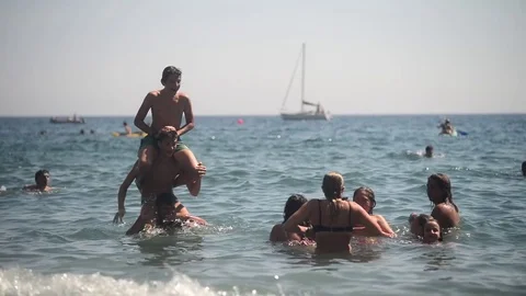Liguria Italy sea Shore Beach and Rocks - People sunbathe, relax and Swim Stock Footage