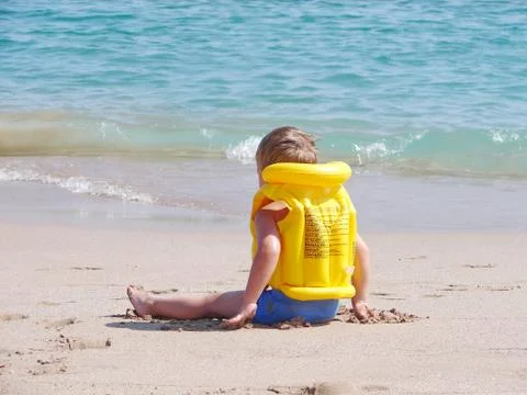 Liitle boy on the beach in lifejacket Stock Photos