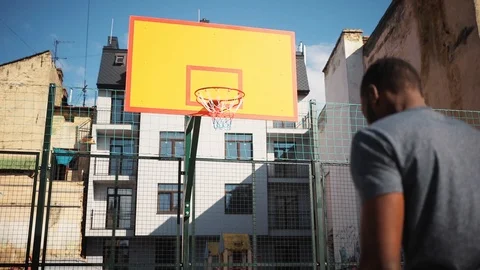 Likable African guy trying to throw a ball in a basketball hoop. Handsome young Stock Footage 92055135