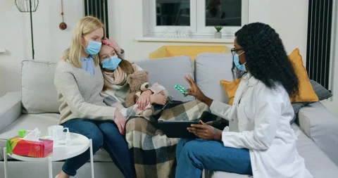 Likable experienced young black-skinned female doctor in mask giving tablets to Stock Footage 144678681