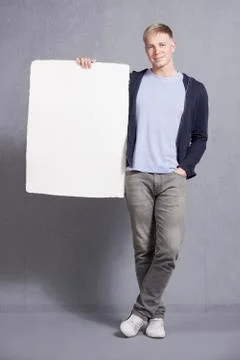 Likable man presenting white empty signboard. Stock Photos