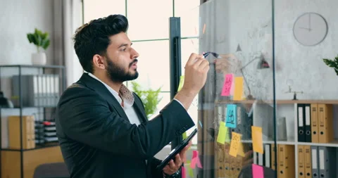 Likable positive confident experienced bearded worker writing with marker on Stock Footage 157990236