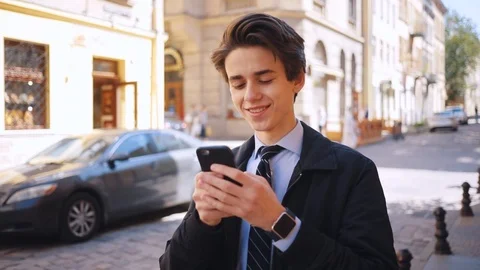 Likable Ukrainian guy looking at screen of black smartphone, chatting. Young Stock Footage 92059074