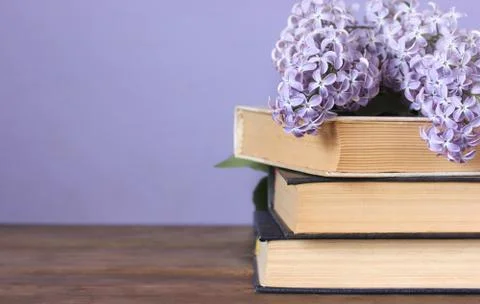 Lilac and a stack of books on the table. Copy space. Stock Photos