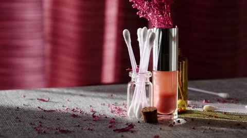 Lilac petals falling over the cosmetics jars and lipstick on the makeup table Stock Footage 149716628