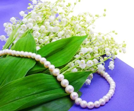 Lilies of the valley an pearl necklace on blue isolated Stock Photos