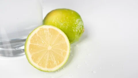 A lime chopped in half against a clear drinking glass and white background Stock Footage 88512618