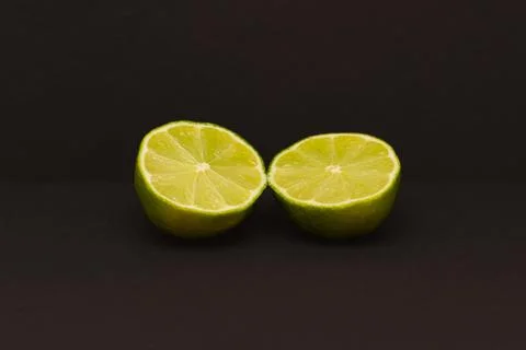 The lime, cut into two halves, lies on a dark background. Stock Photos