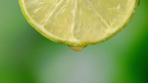 Lime with dripping clear juice on green background Vídeos de archivo 248783201