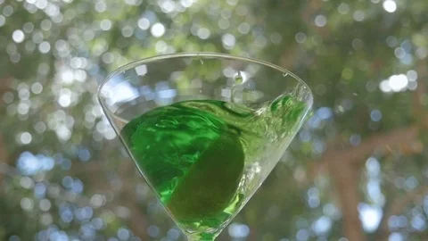 A Lime Drops into a Bright Green Appletini in Slow Motion Stock Footage 75914600