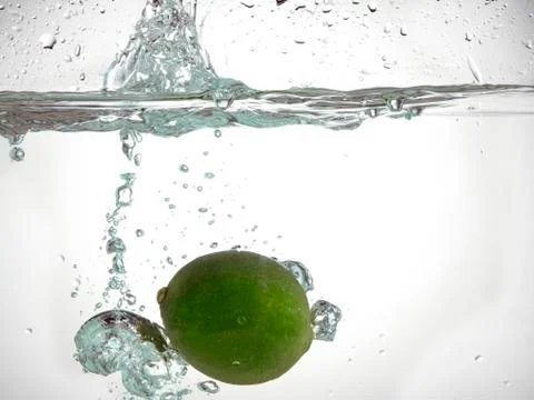Lime falling in clear water Stock Photos