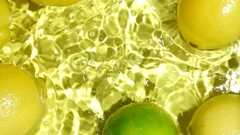Lime falling into water with lemons, creating a splash in slow motion. Stock Footage 345655963