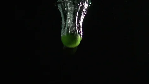 Lime falling into water shot against black background Stock Footage 81016653