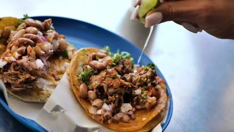Lime juice is dripped onto a serving of two delicious Mexican tacos, Stock Footage 147406618