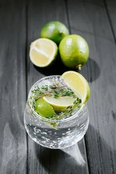 Lime lemonade with thyme, ginger and ice. wooden dark background. Flashy food 库存照片