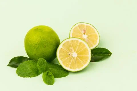 Lime with mint leaves isolated on light green background. Stock Photos