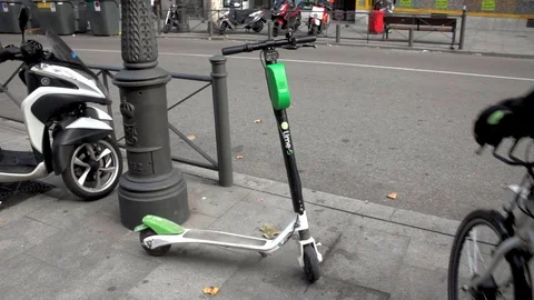 Lime s electric sharing scooter parked while a deliveroo delivery sets off Stock Footage 97498082