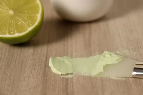 Lime slice and green paste on wooden table in kitchen during food preparation Foto stock