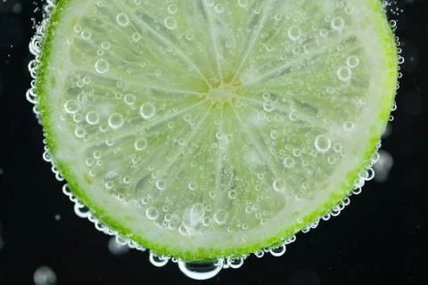 Lime slice falling into water Stock Photos