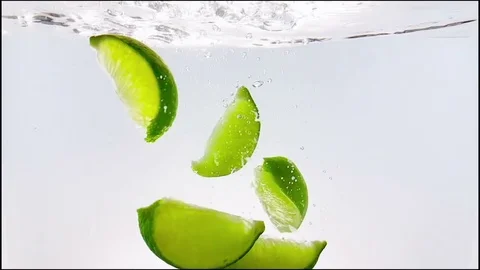 Lime slice fruit splash falling down into white cocktail and water Stock Footage 76199025