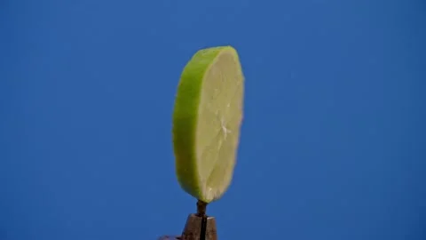 Lime slice spinning on blue screen 库存影片 220755809