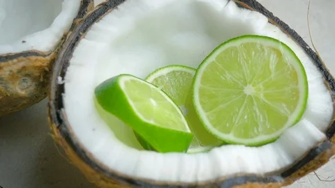 Lime Slices Fall into a Coconut Half in Slow Motion Stock Footage 90153607